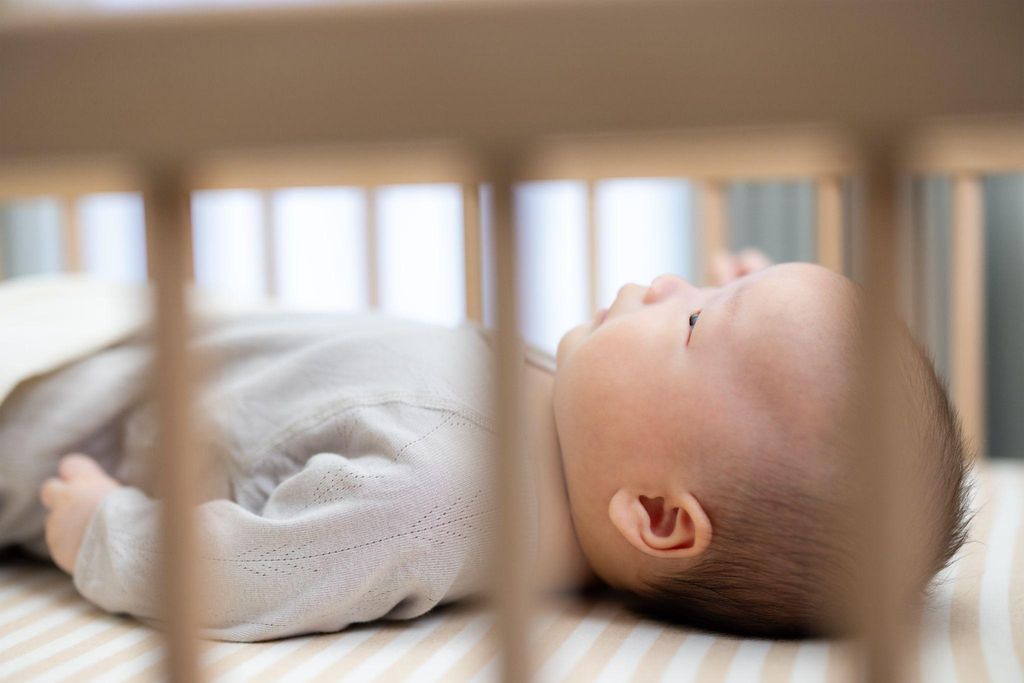 A baby sleeping safely in their cot following safe sleep guidelines.