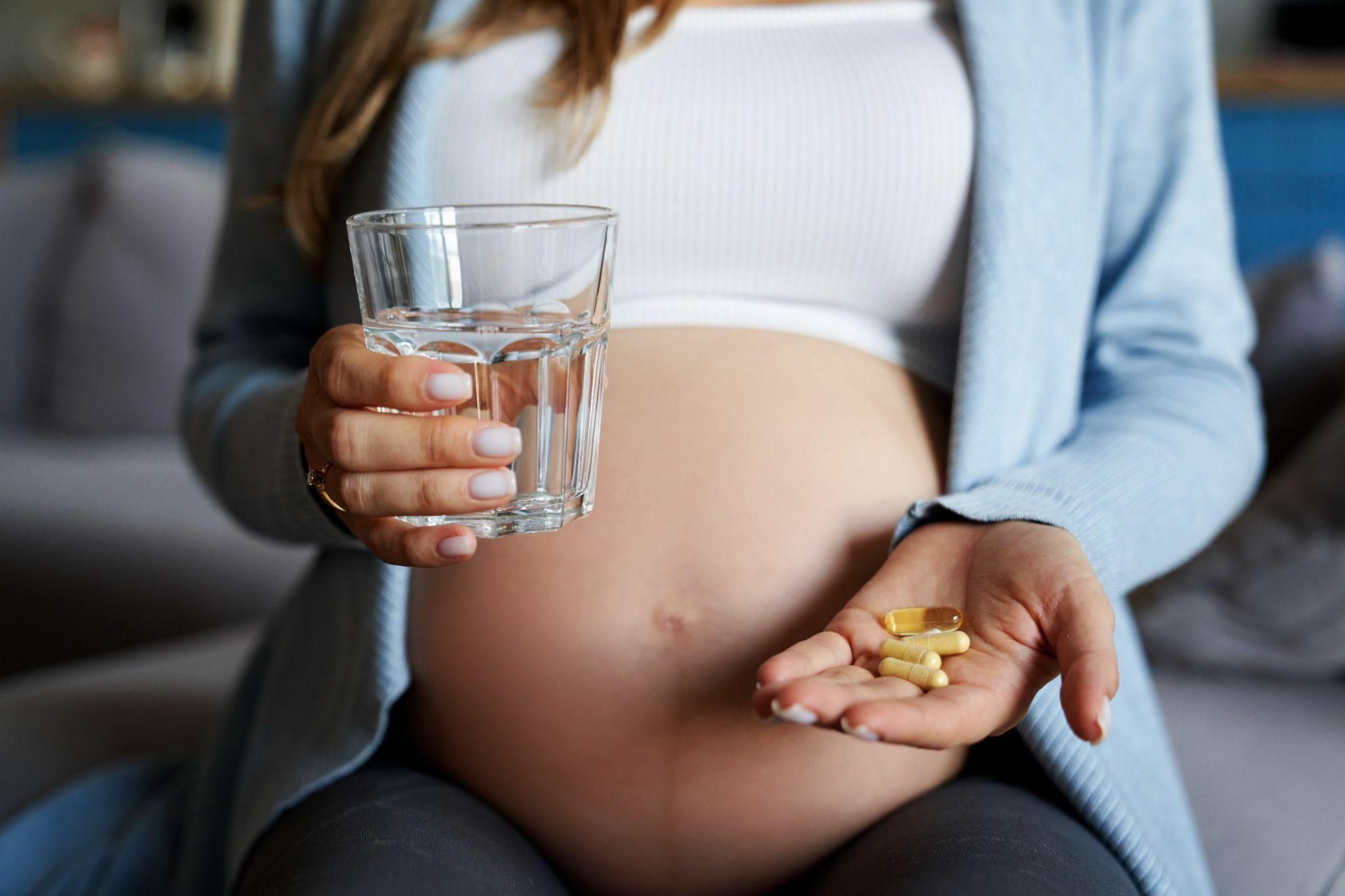 Pregnacare vitamins with a smiling pregnant woman in the background.