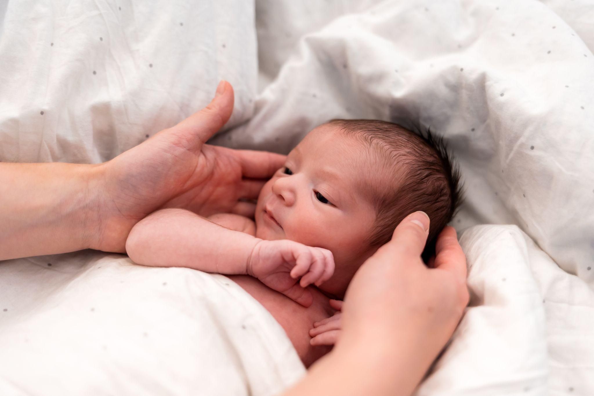 Hailey Bieber holding her newborn baby and smiling alongside Justin Bieber.