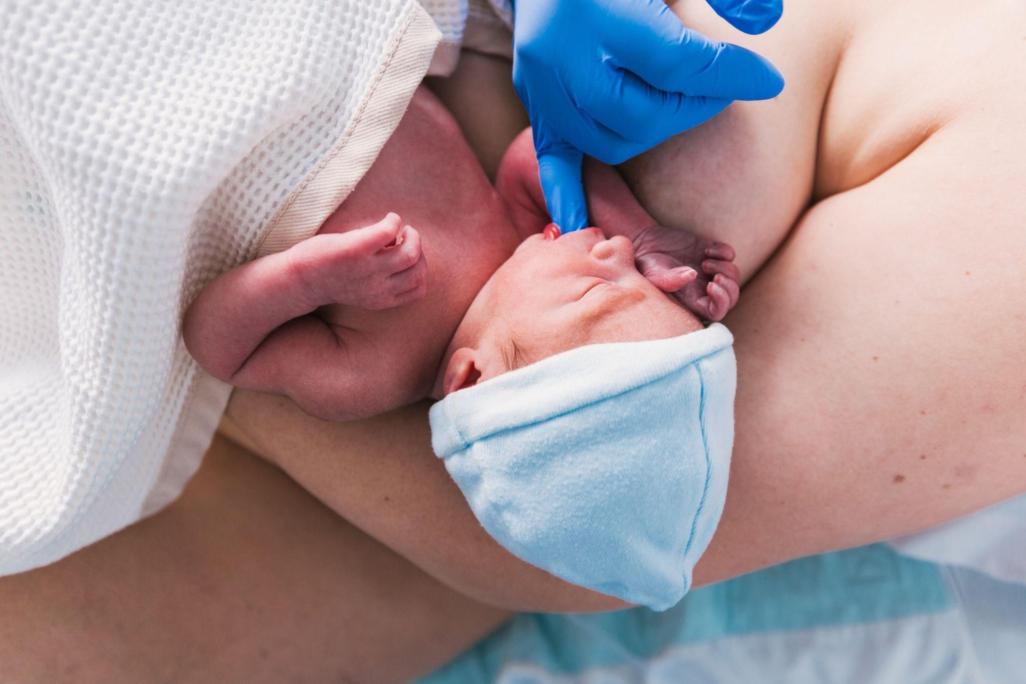 Newborn baby’s reflexes are tested by midwife after birth in hospital.