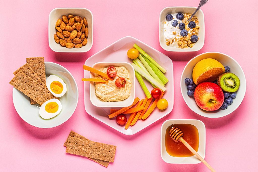 Healthy pregnancy snacks such as hummus with veggies, fruit salad, and avocado toast.