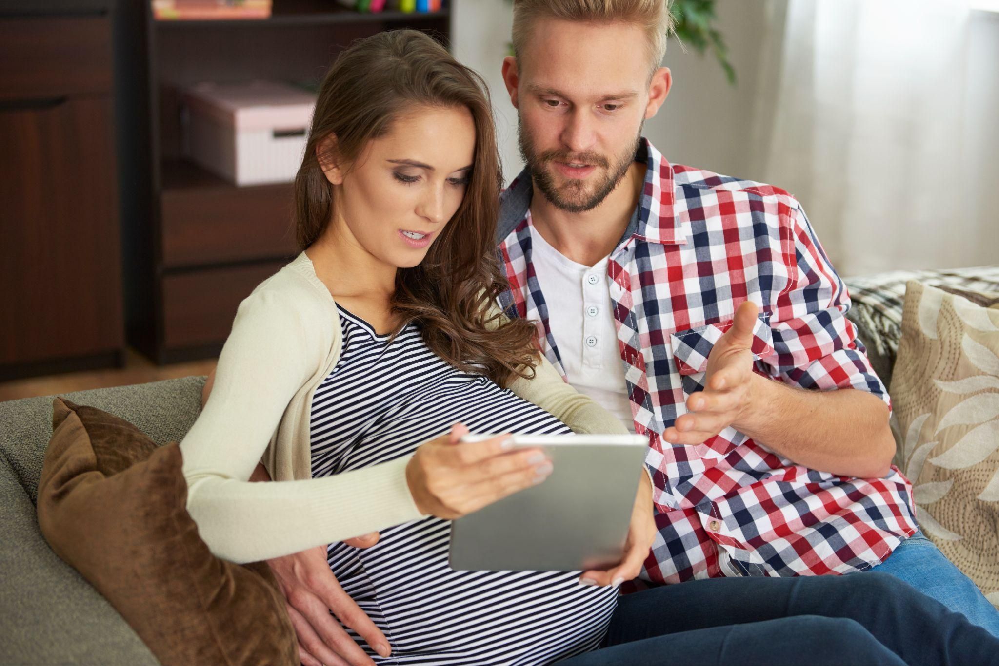 Parents-to-be discussing their baby budget with an iPad.