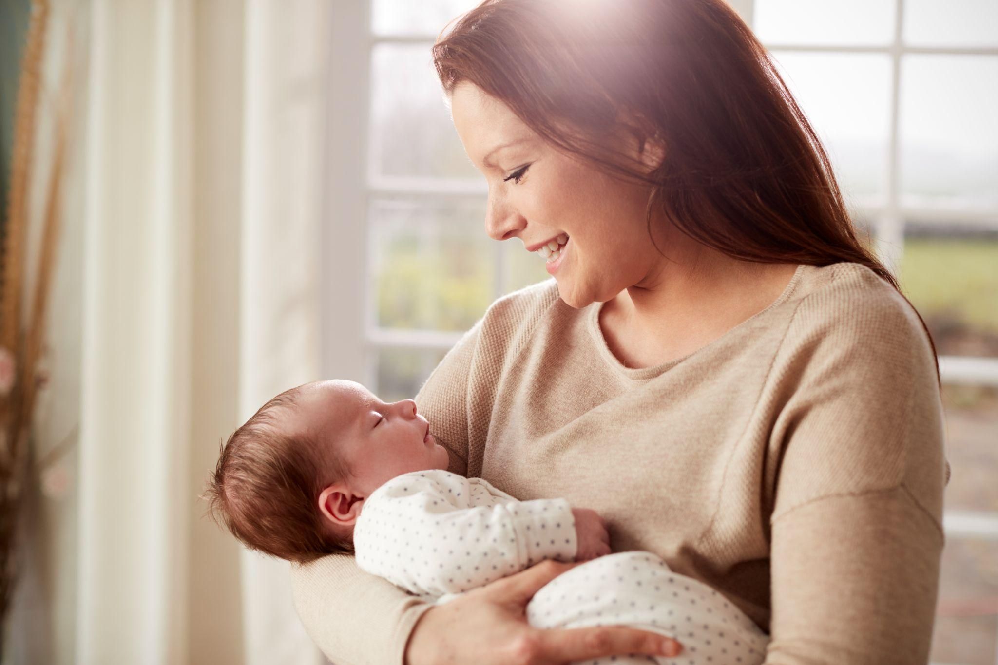 New mum cuddles her baby at home in the postnatal period.