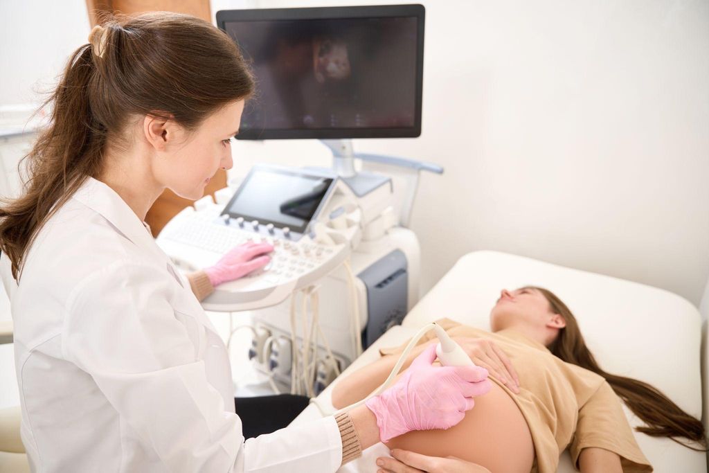 Pregnant woman in second trimester has ultrasound scan during routine appointment at her antenatal clinic.