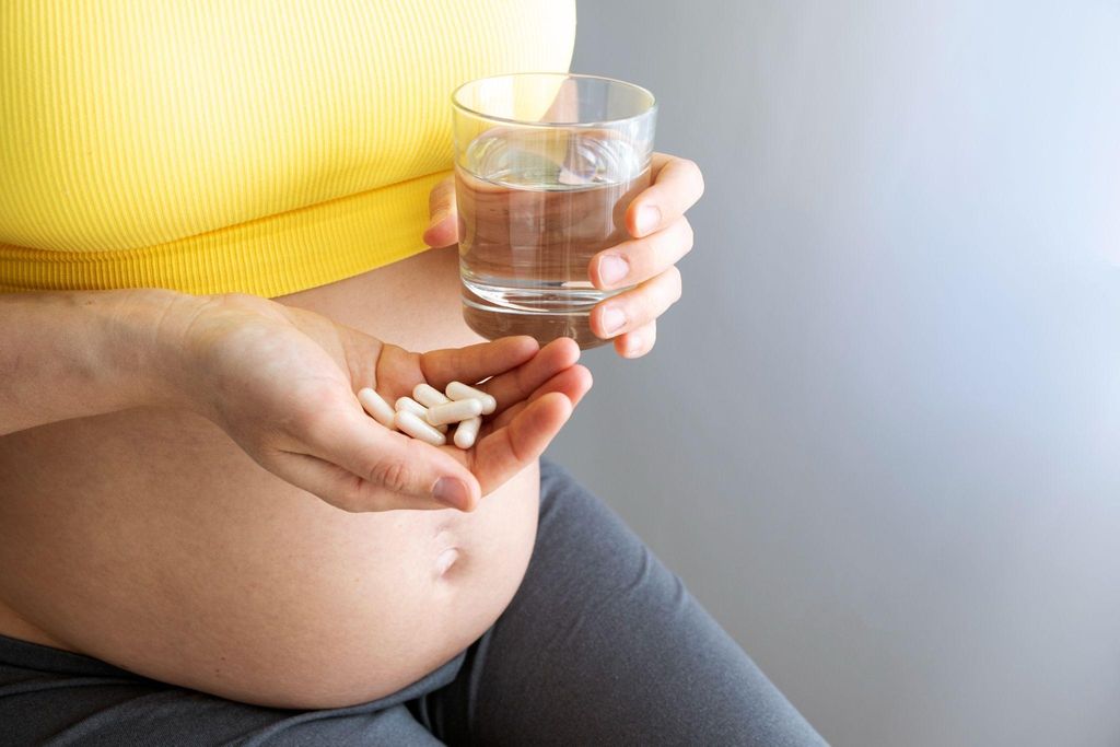 Pregnacare vitamins with a smiling pregnant woman holding her belly in the background.