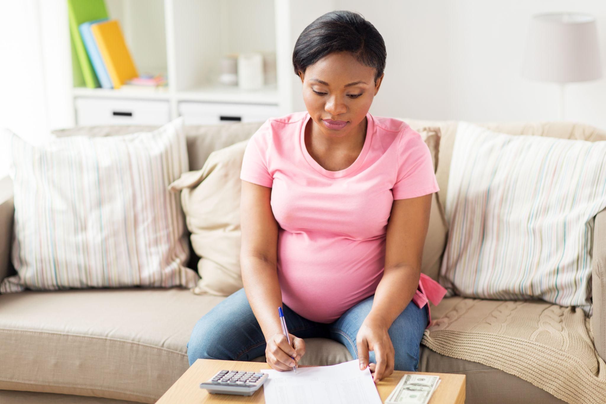 Parents discussing their baby budget with a notebook and calculator.