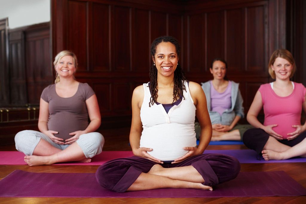 Pregnant woman practising positions for labour with prenatal yoga.