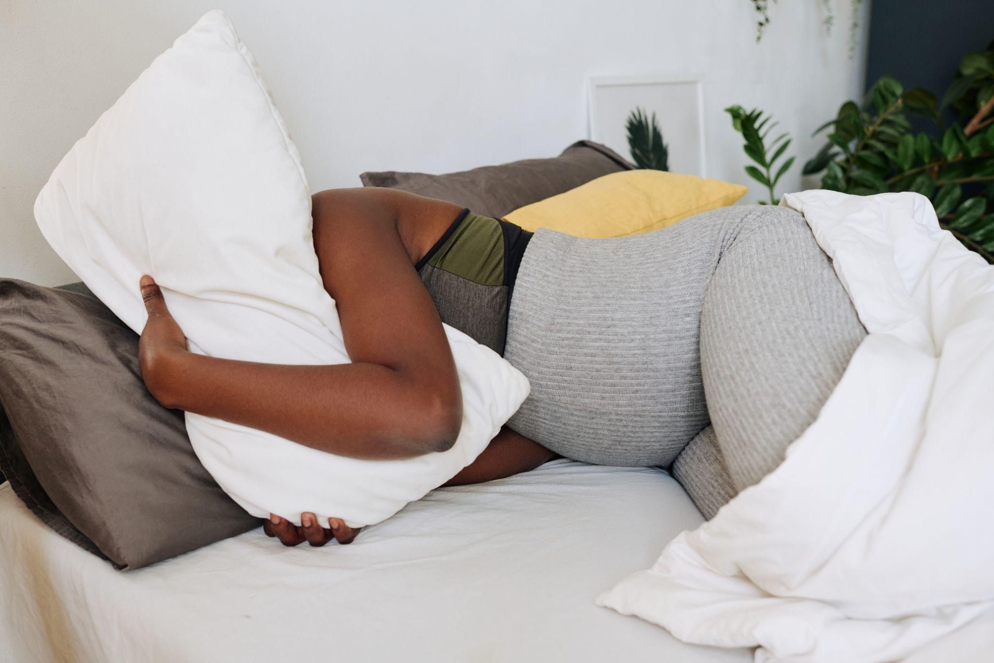 A pregnant woman resting in bed while her partner sleeps in a separate bed.