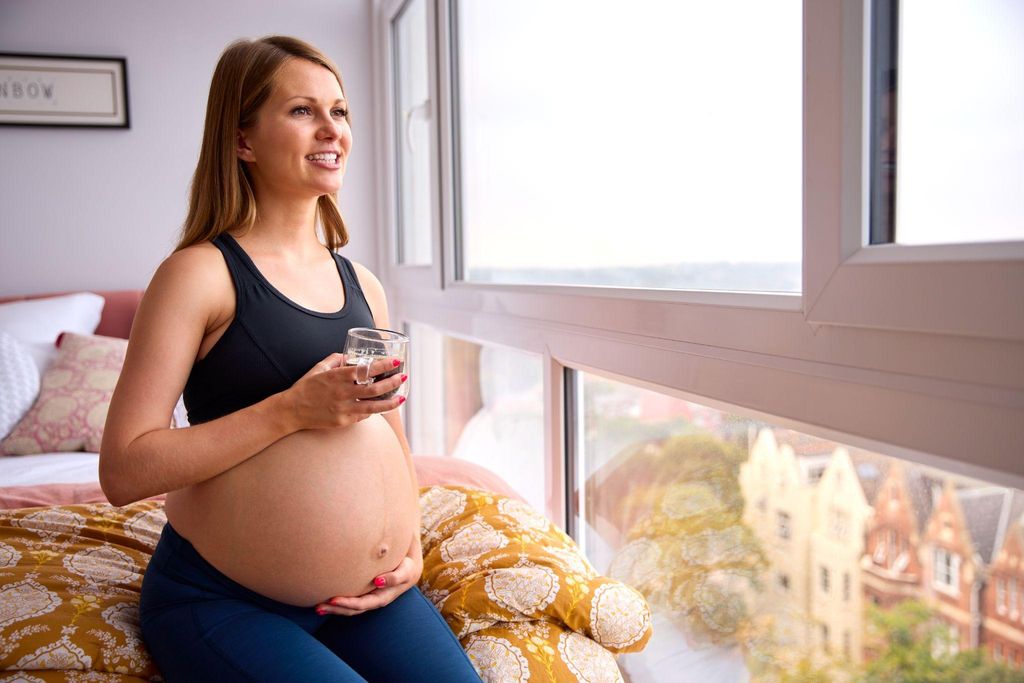 Pregnant woman enjoys a small cup of coffee as part of her antenatal diet.