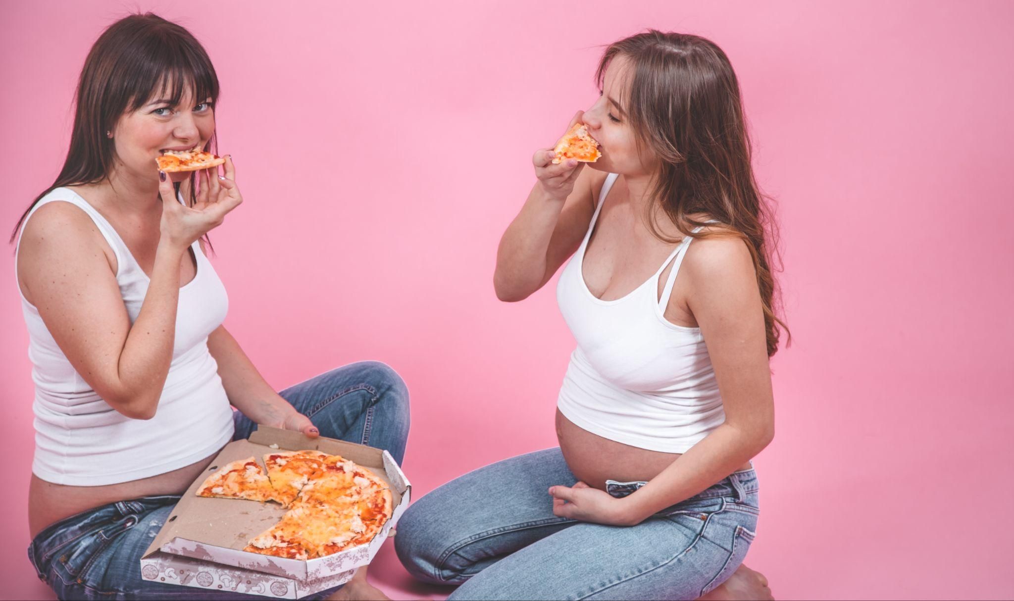 Pregnant women eating pizza.