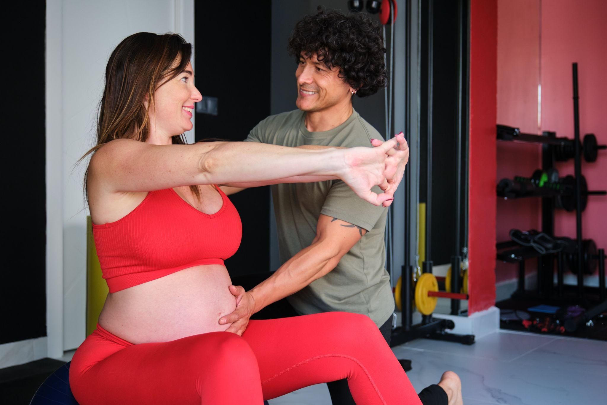 A pregnant woman demonstrating safe lifting techniques, using proper posture and bending her knees.