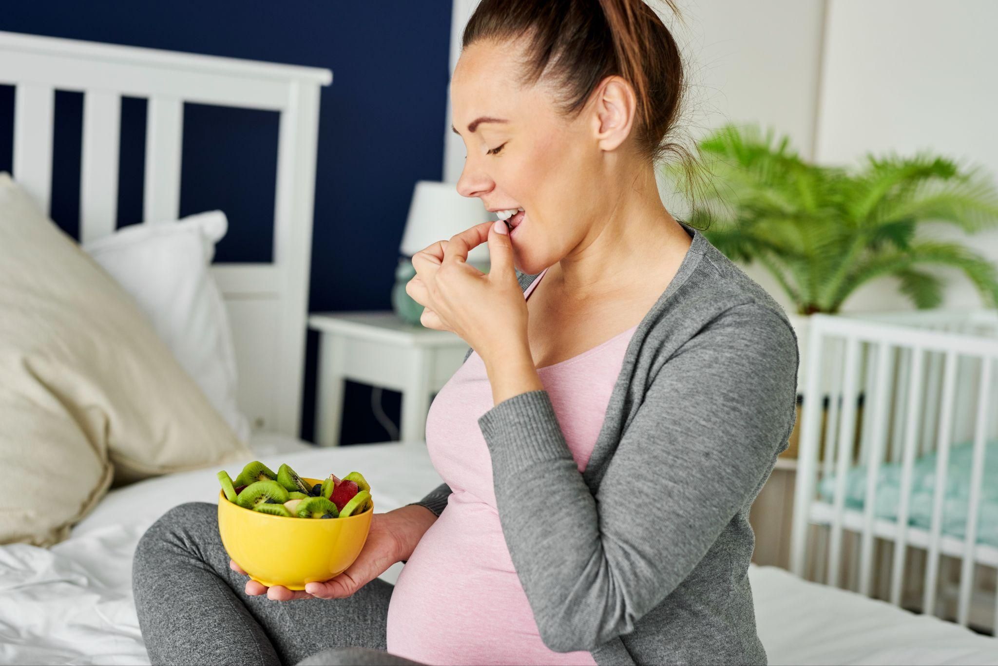 Pregnant woman enjoys a kiwi and apple salad as part of her antenatal diet.