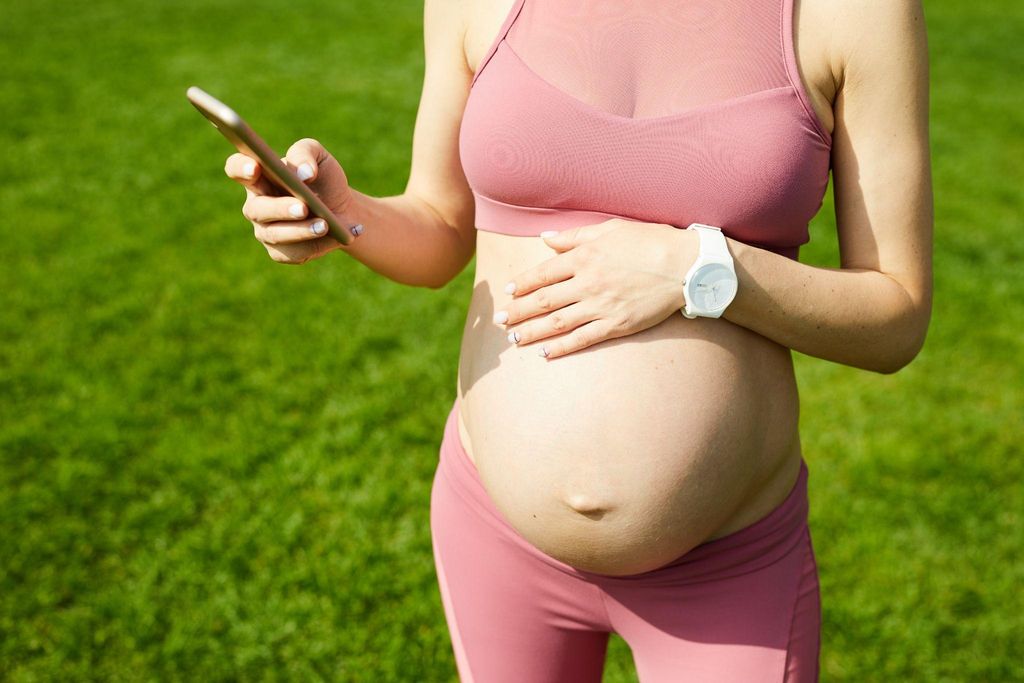 Pregnant woman using social media for antenatal education during yoga.