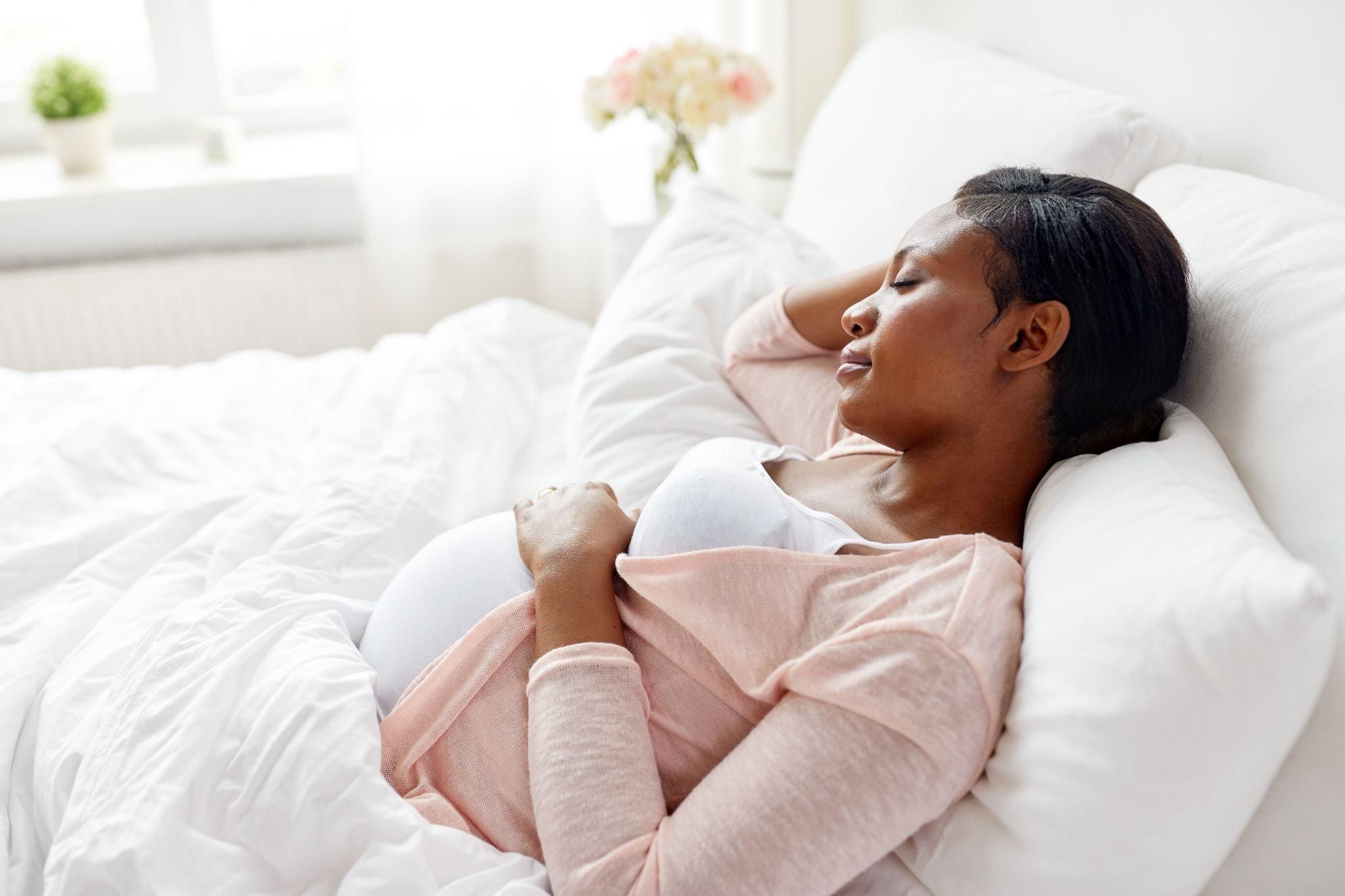 A pregnant woman resting comfortably on her side with supportive pillows.