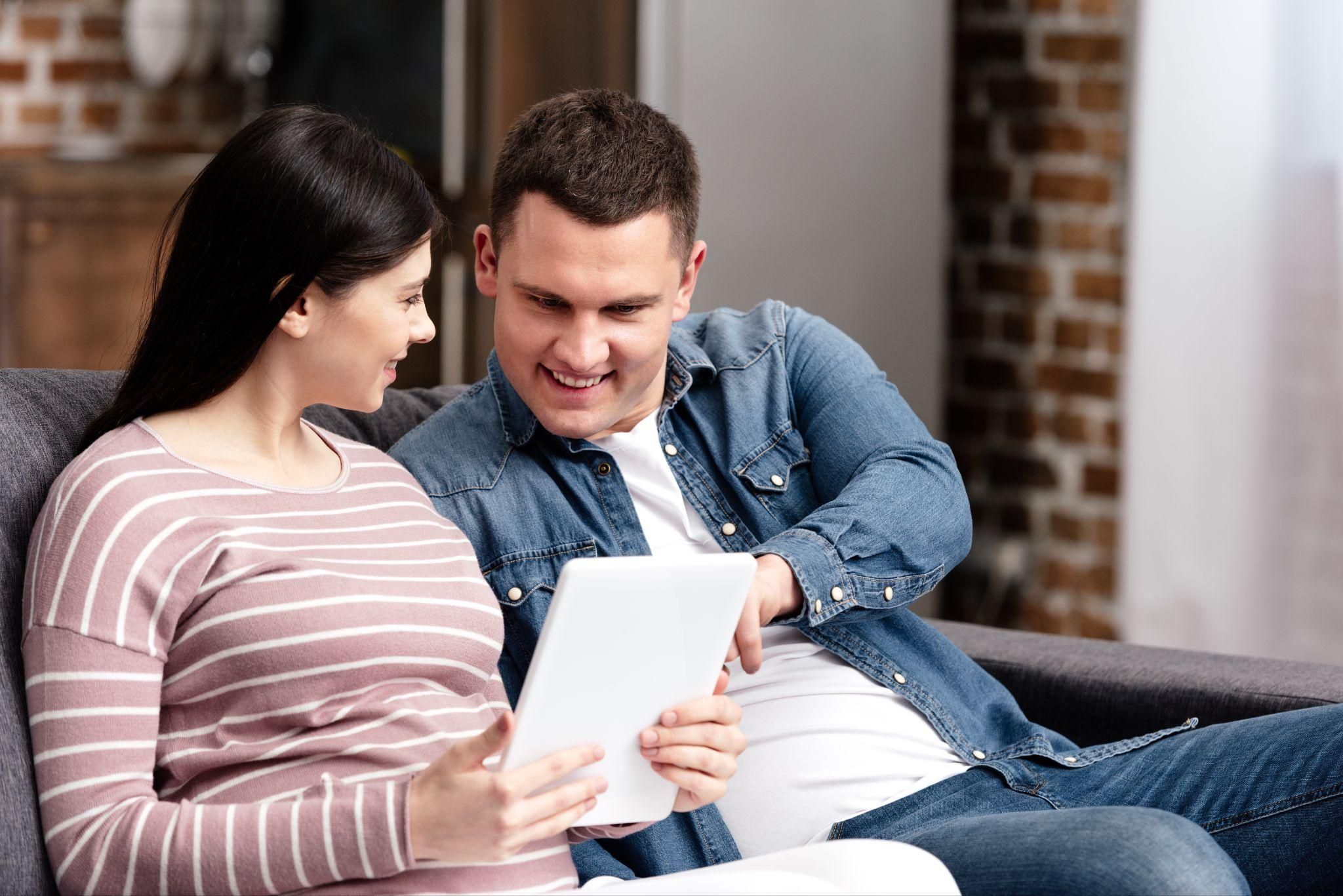 Expectant parents discussing an antenatal birth plan with a notebook and pen.