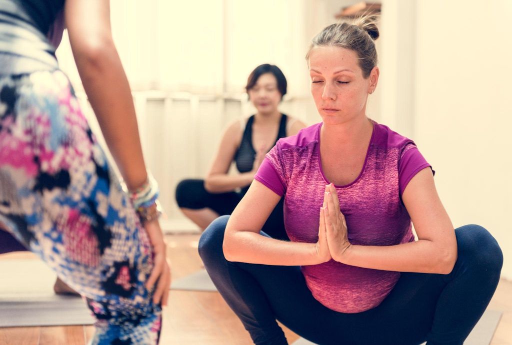 A pregnant woman practising antenatal yoga in a calm home setting, focusing on stretching and breathing exercises.