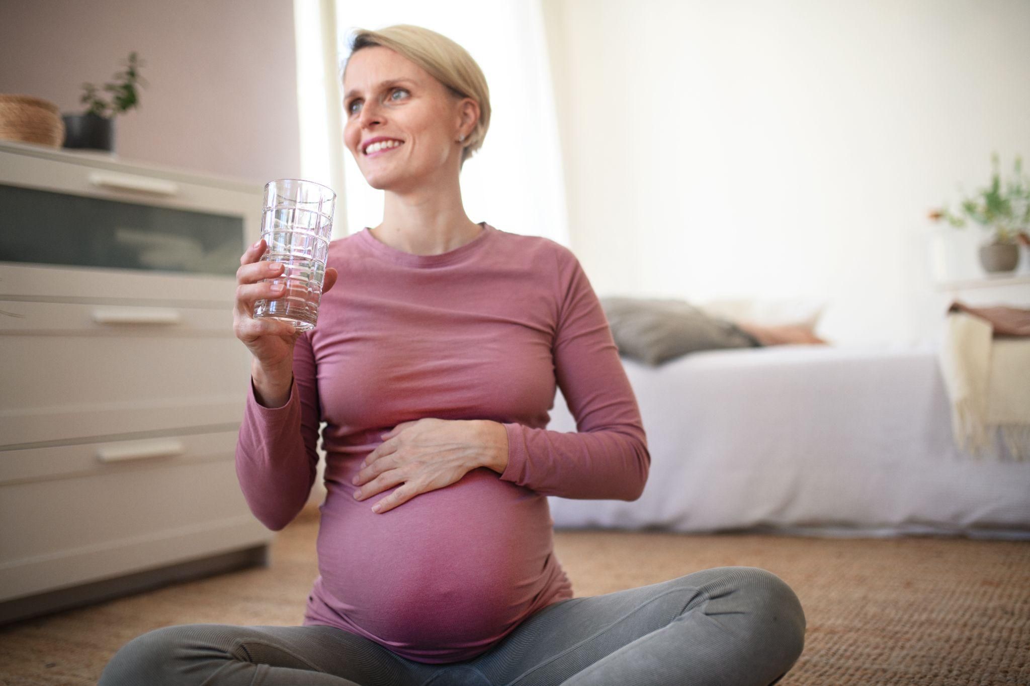 Pregnant woman enjoys a glass of water as part of her antenatal diet.