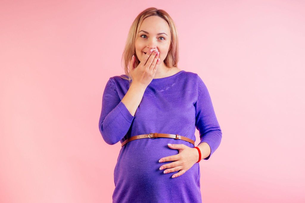 Pregnant woman talking to a midwife during an antenatal checkup about pregnancy symptoms.