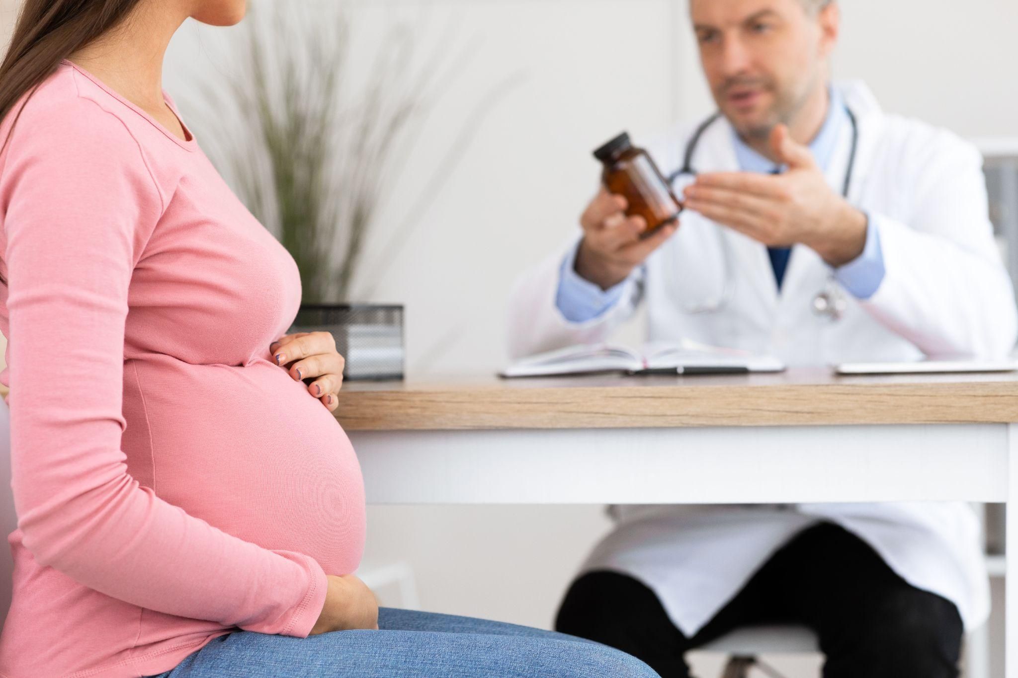 Pregnant woman speaks to doctor about prenatal vitamins during antenatal clinic appointment.