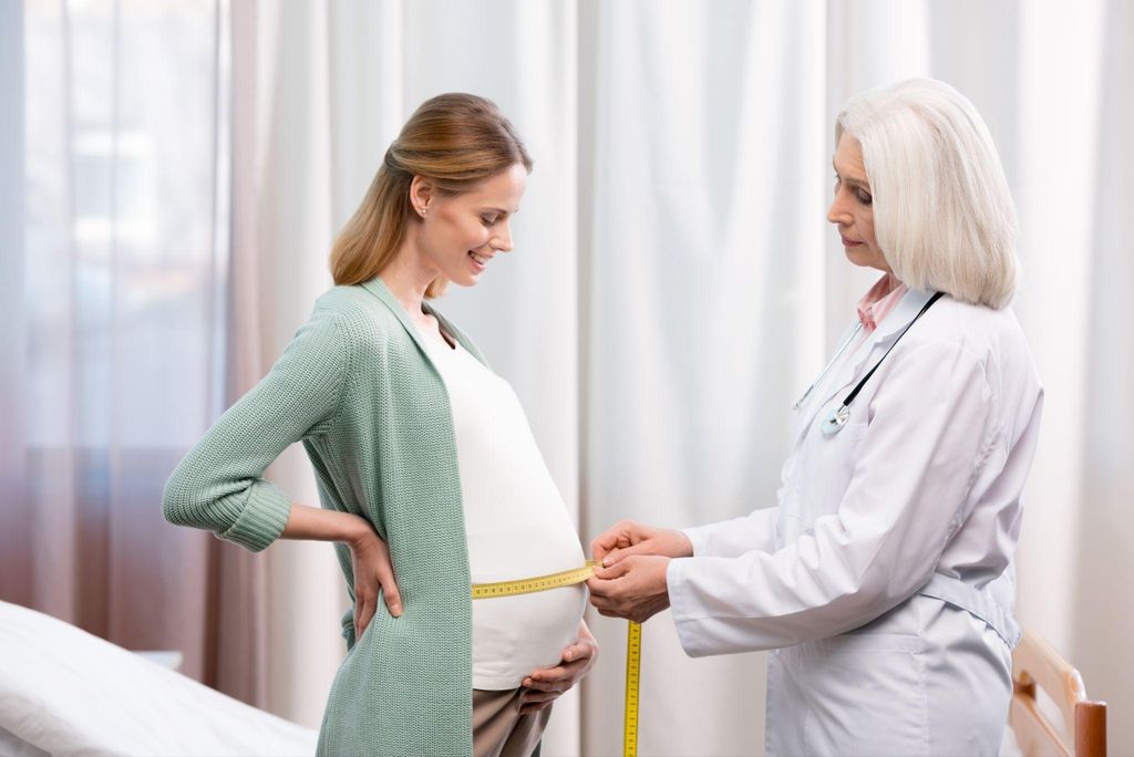 Pregnant woman’s bump is measured with tape by doctor, to assess how the baby is growing, as part of her antenatal care.