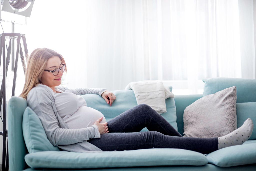 Pregnant woman struggling with morning sickness, supported by her partner.