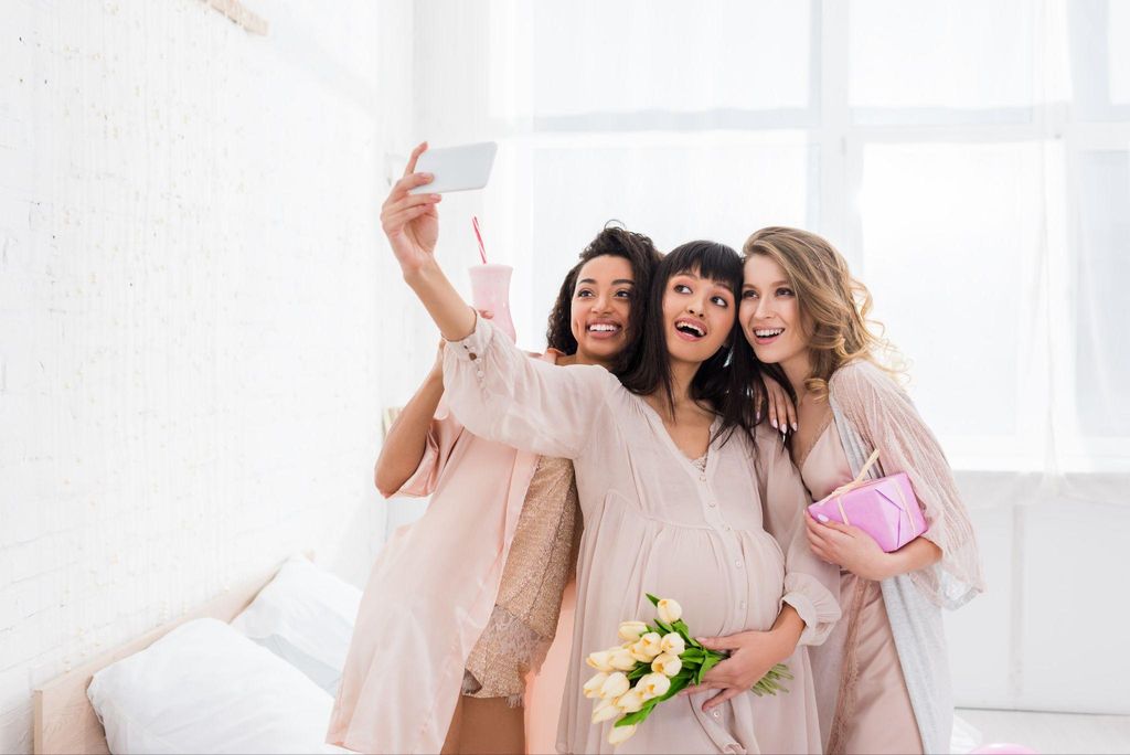 Pregnant woman takes selfie with friends.