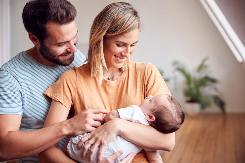 New parents sharing a laugh while caring for their baby.