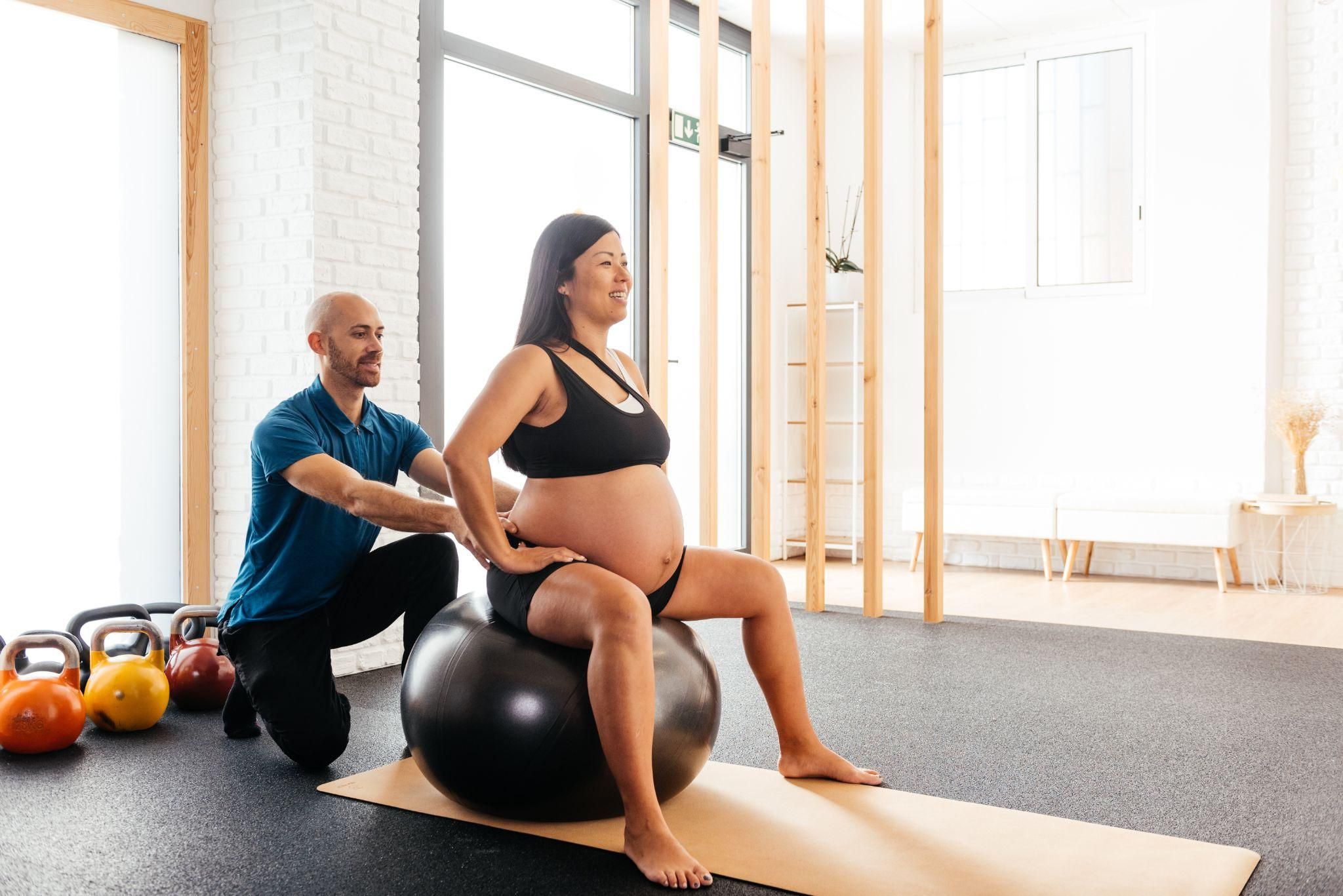 A pregnant woman sitting upright on a yoga ball with proper antenatal posture to reduce back pain.