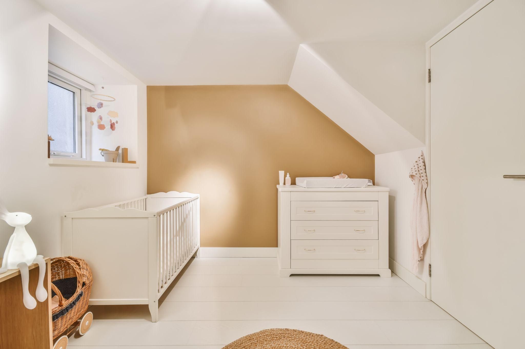 A stylish and functional nursery designed with soft lighting, cosy furniture, and practical storage.