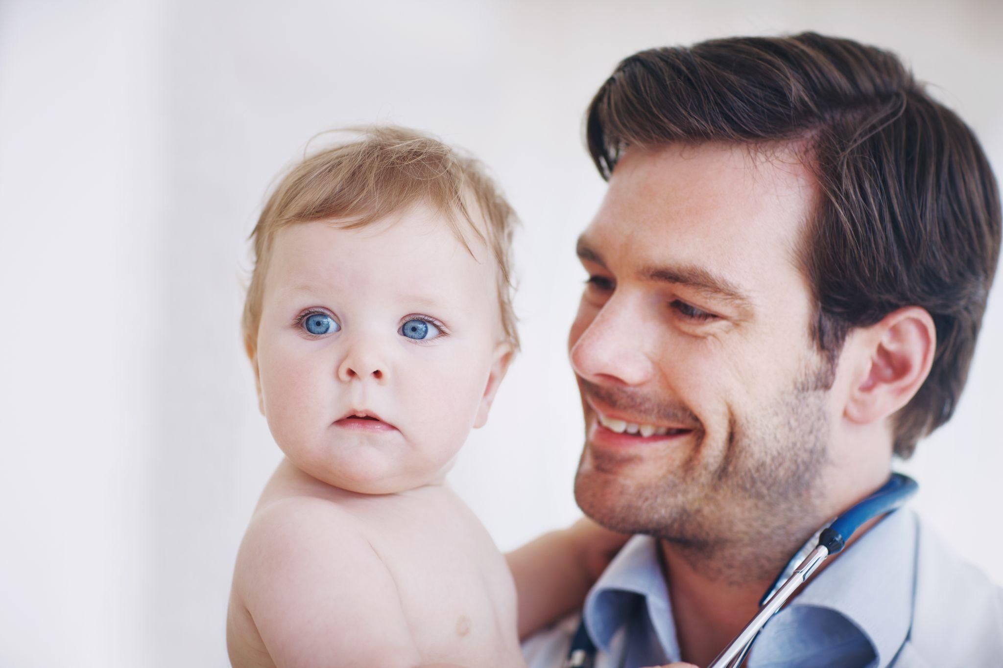 A father engaging with healthcare professionals during a postnatal appointment.