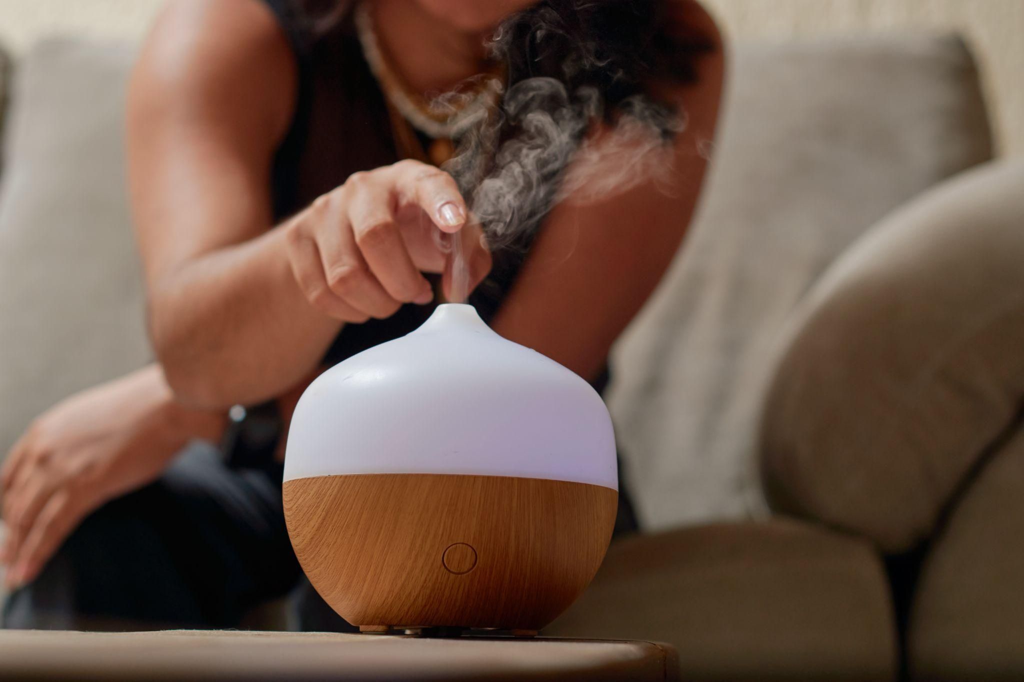 Pregnant woman practicing relaxation with aromatherapy oils and a diffuser.