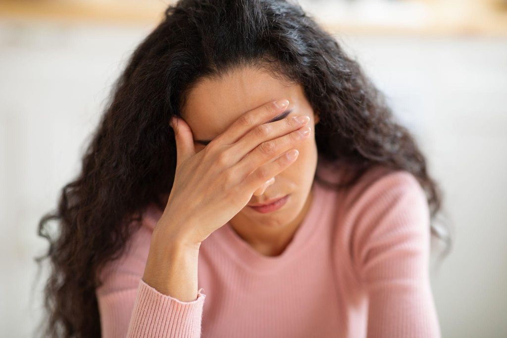 Woman with antenatal depression puts head in hand. Persistent sadness is a well-known symptom of depression.