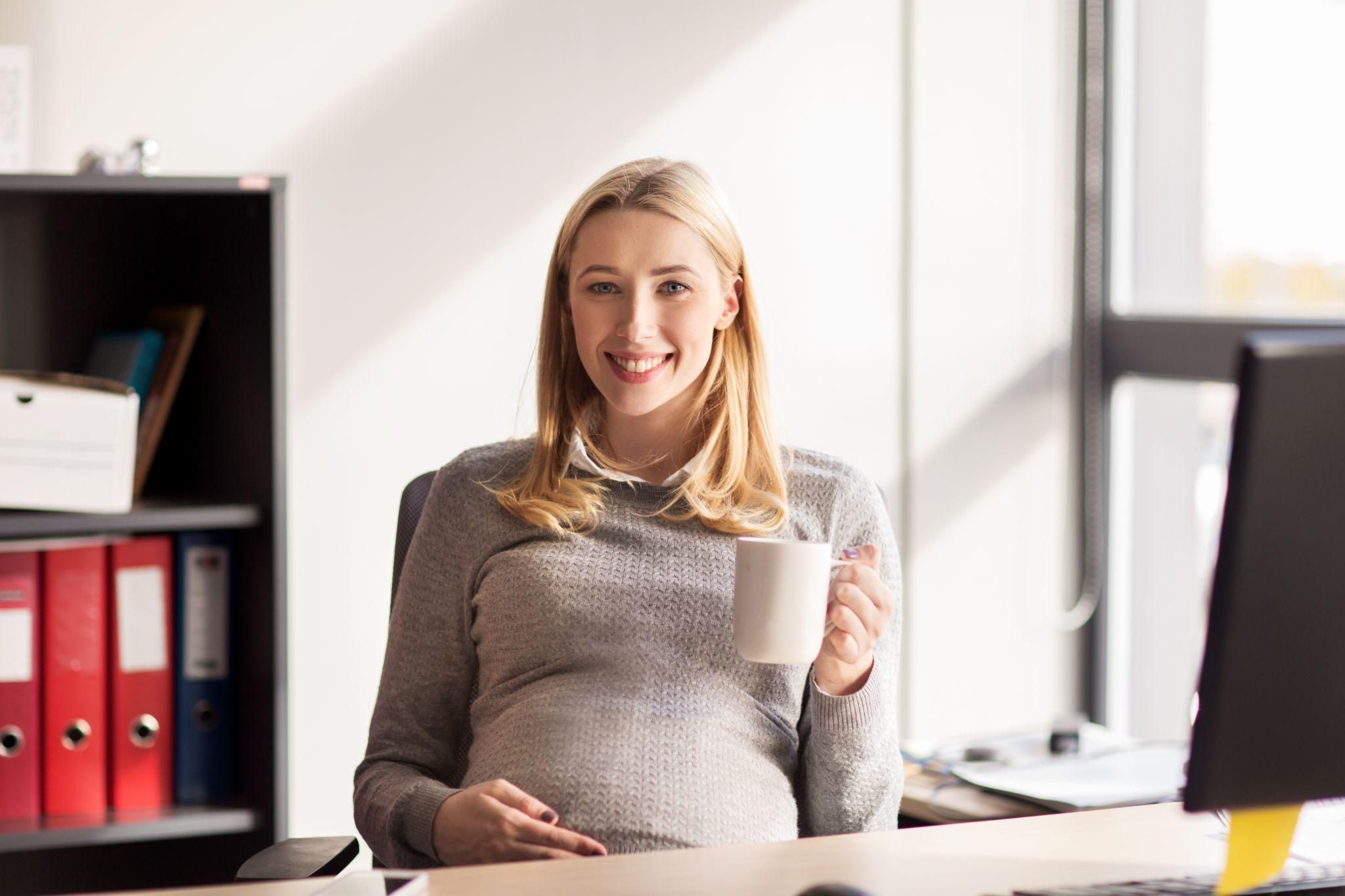 A working mother-to-be taking a moment to breathe deeply and manage her emotions at the office.