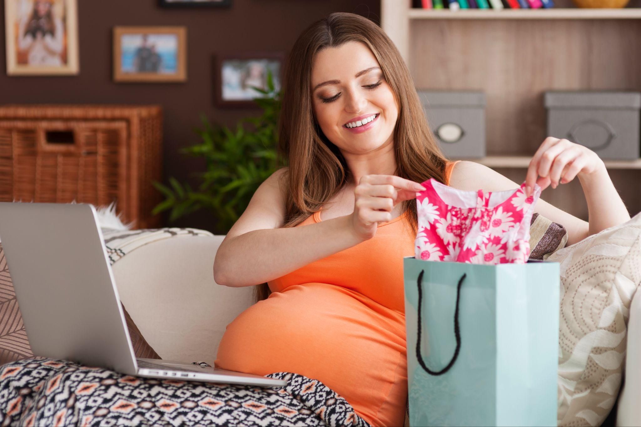 A budgeting tool for newborn costs displayed on a laptop next to baby items.