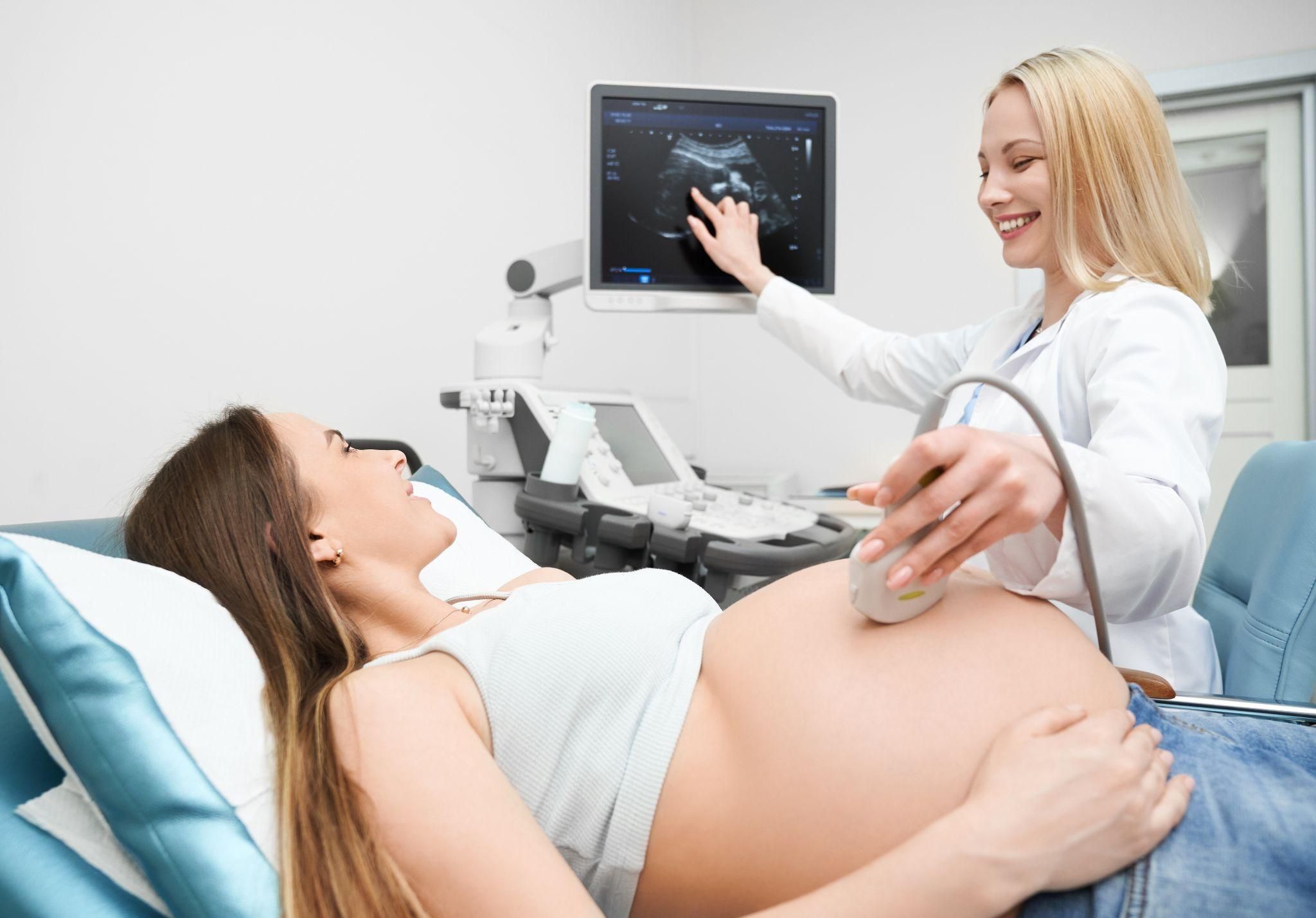 Pregnant woman has ultrasound scan with obstetrician during antenatal appointment.