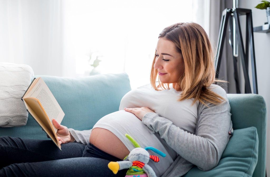 Expectant parent learning about childbirth and baby care from an antenatal text.