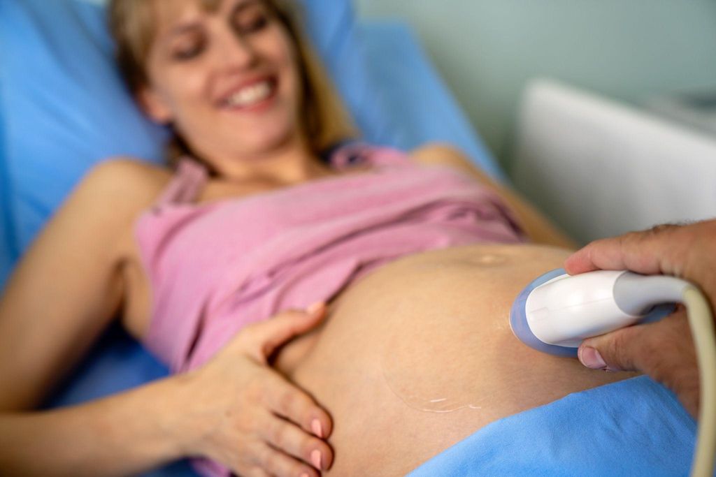 A pregnant woman receiving an ultrasound scan during an antenatal appointment.