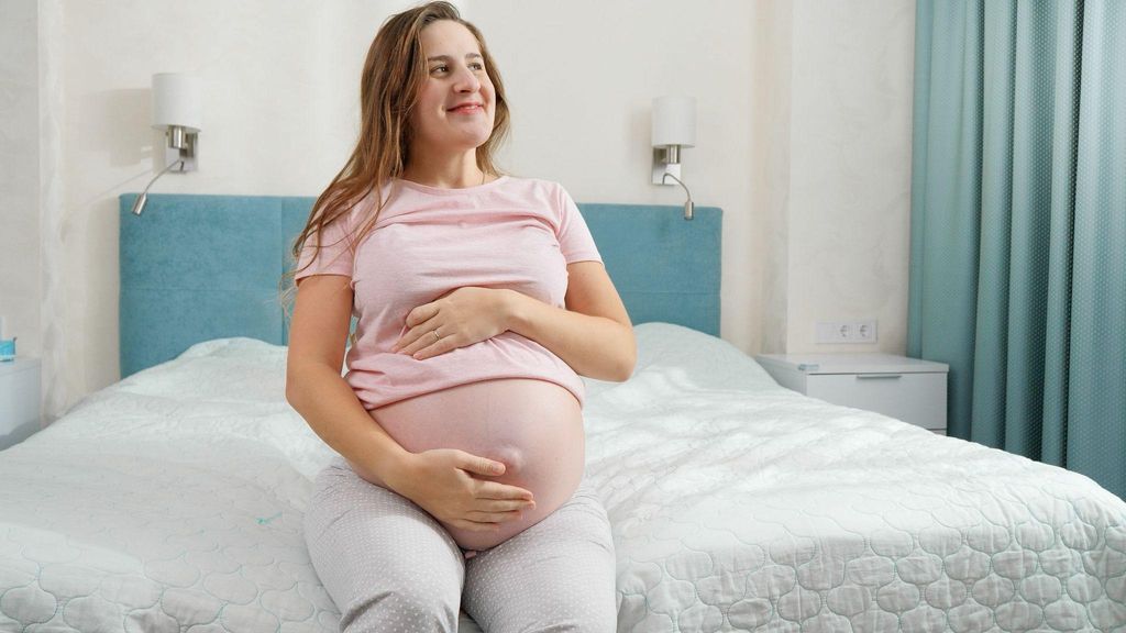 Pregnant woman on bed rest, being checked on by her midwife during an antenatal appointment.