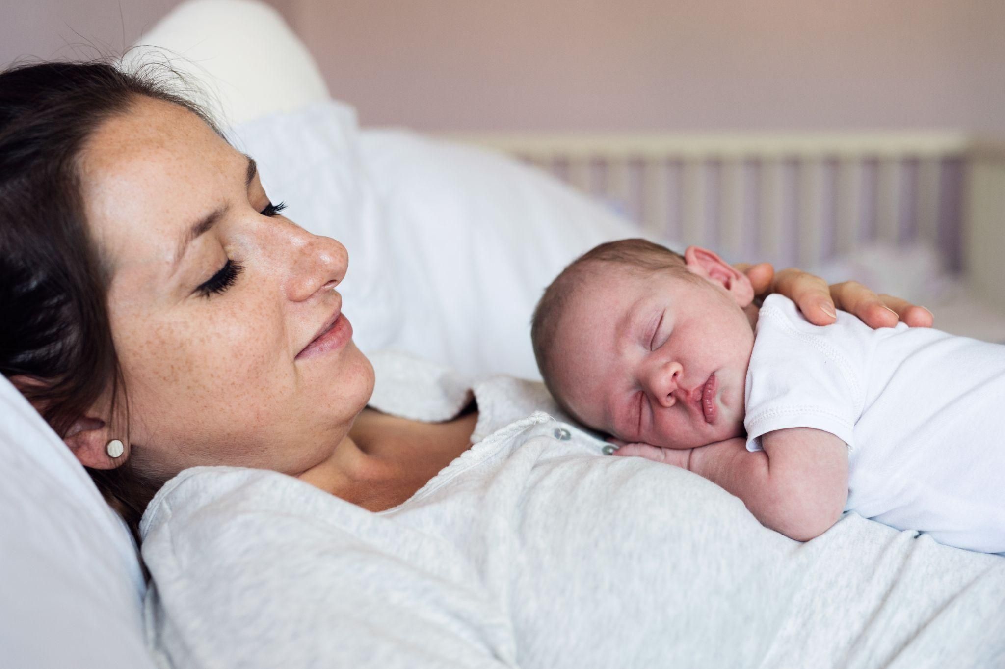 A supportive moment between a mother and her newborn, highlighting postnatal recovery.