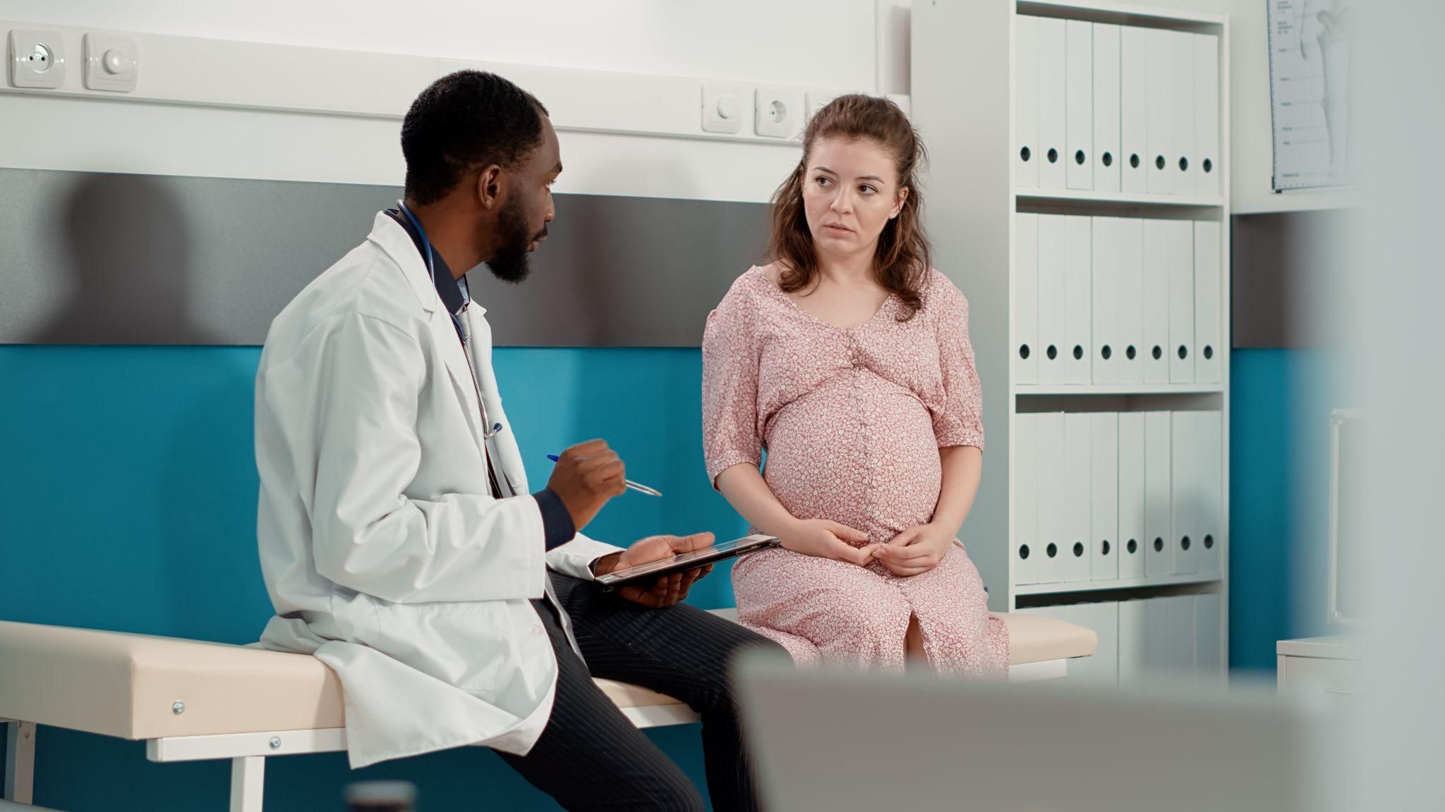 Pregnant woman listening to doctor during antenatal appointment at antenatal clinic.