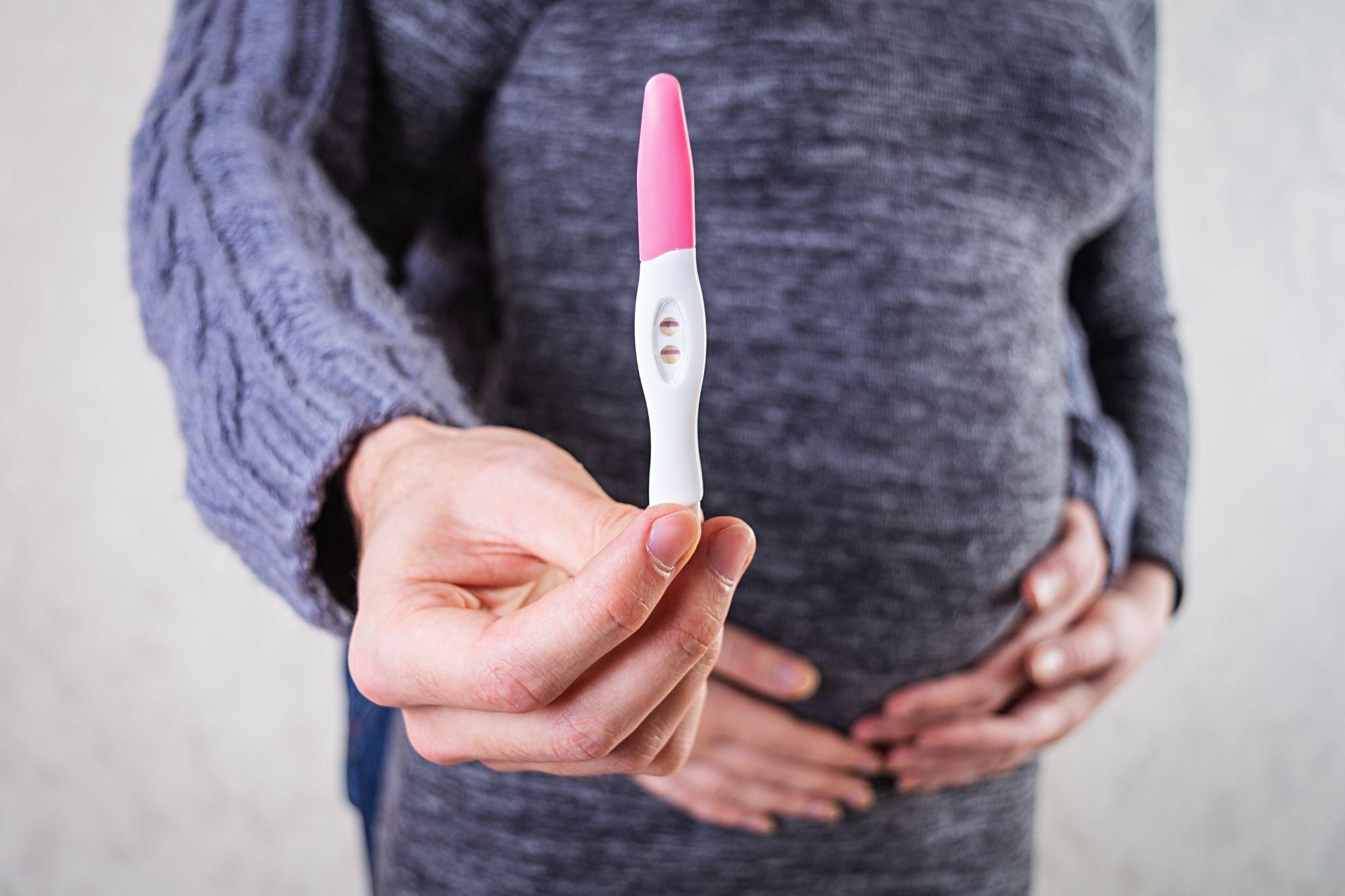 A pregnancy test displaying positive results alongside a calendar with a marked date and antenatal vitamins.