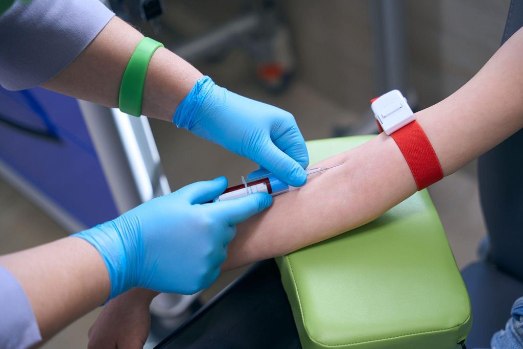 Midwife takes a sample of pregnant woman’s blood for analysis during antenatal appointment.