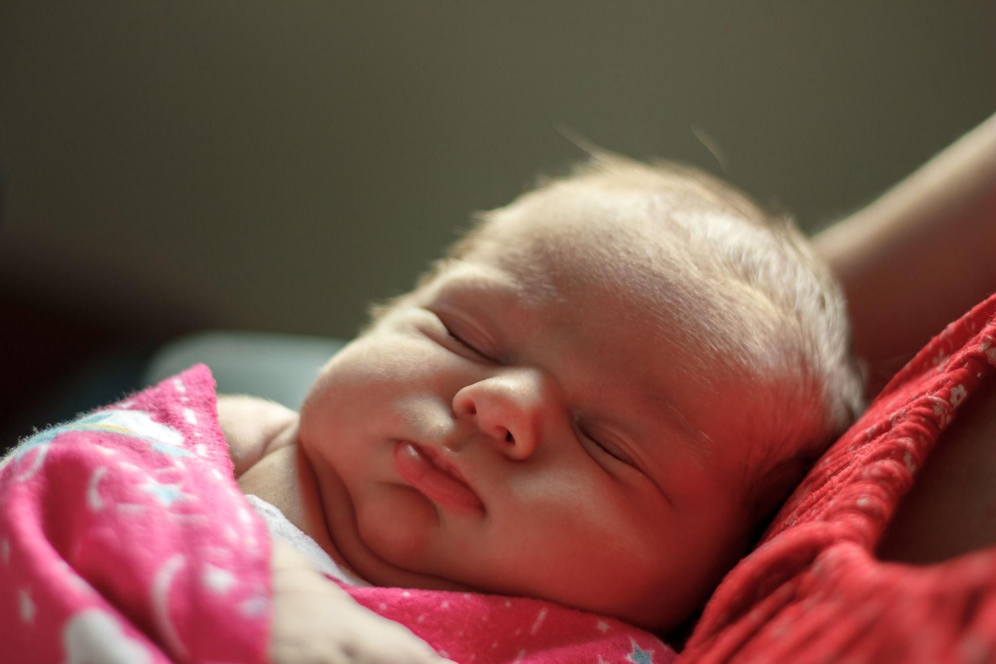 Healthy newborn baby girl sleeping. Antenatal colostrum harvesting can help start your baby’s diet off right.