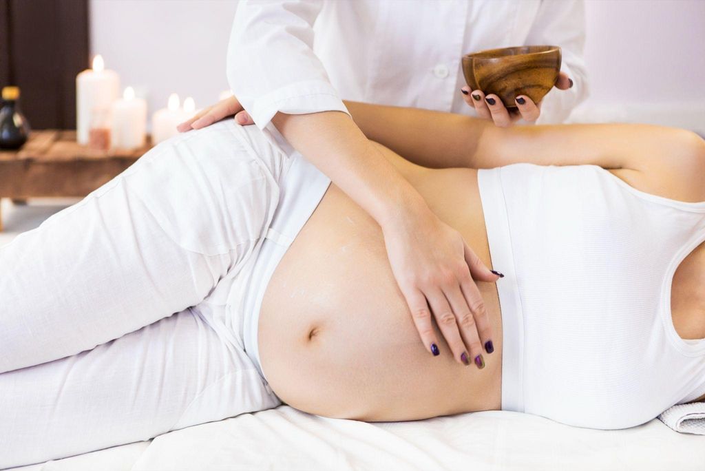 Pregnant woman receiving a relaxing prenatal massage in a soothing environment.