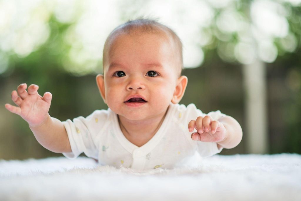 A mother smiling at her baby during tummy time.