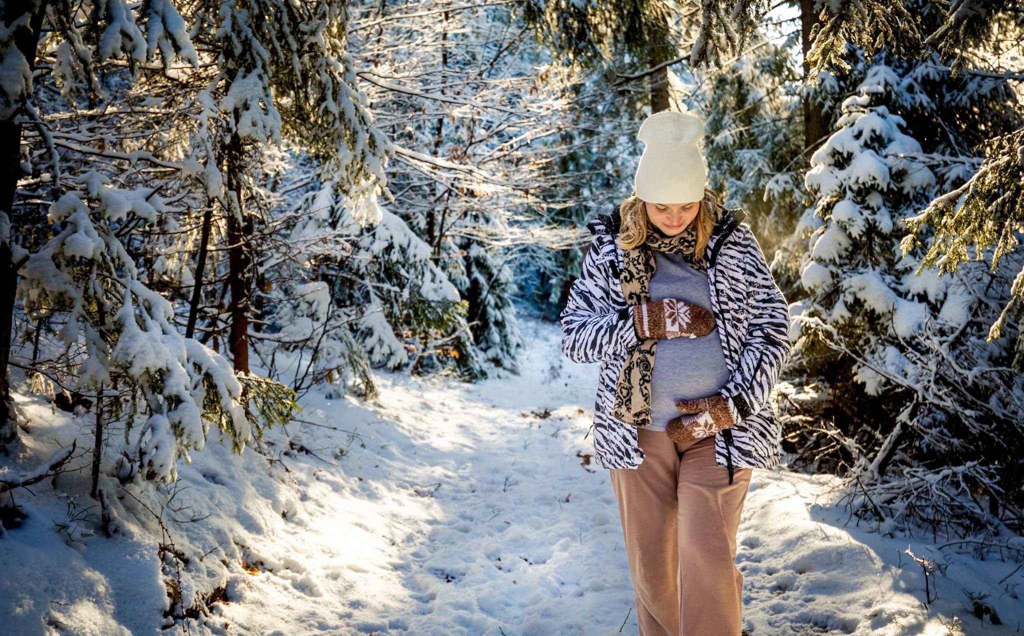 A pregnant woman enjoying skiing with caution on a snowy mountain slope, prioritising safety during pregnancy.