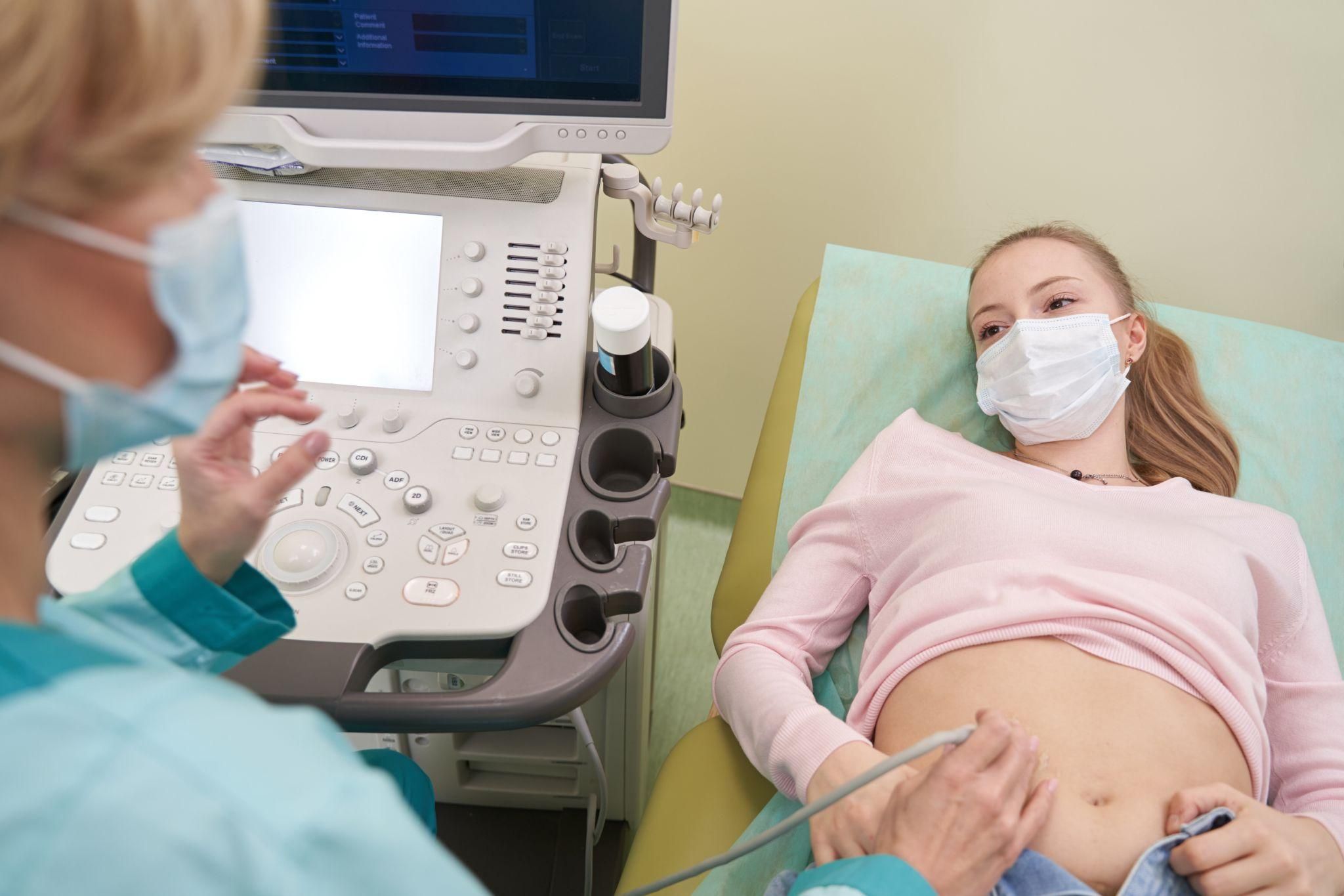 Pregnant woman listens to sonographer during routine antenatal appointment ultrasound scan.