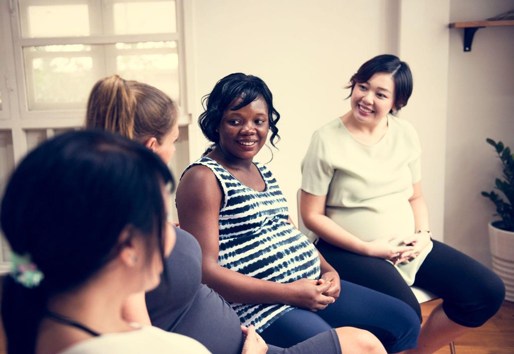 A group of expectant parents attending an antenatal class in London, learning about birth preparation.