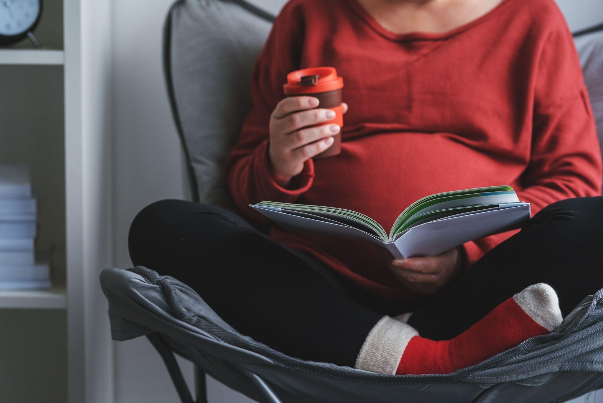 "Pregnant woman reading a childbirth preparation book in a peaceful setting."