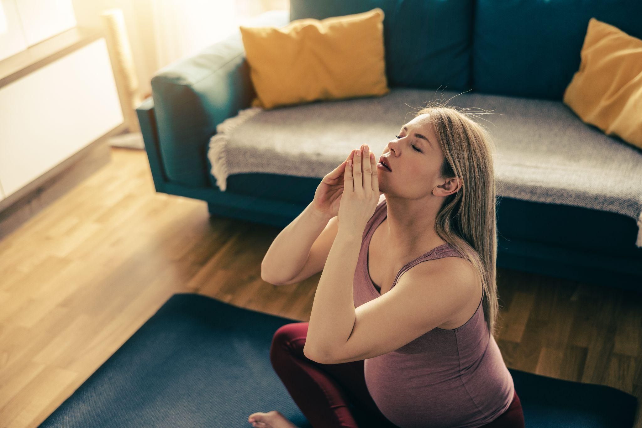 A pregnant woman on a yoga mat, focusing on deep breathing techniques.